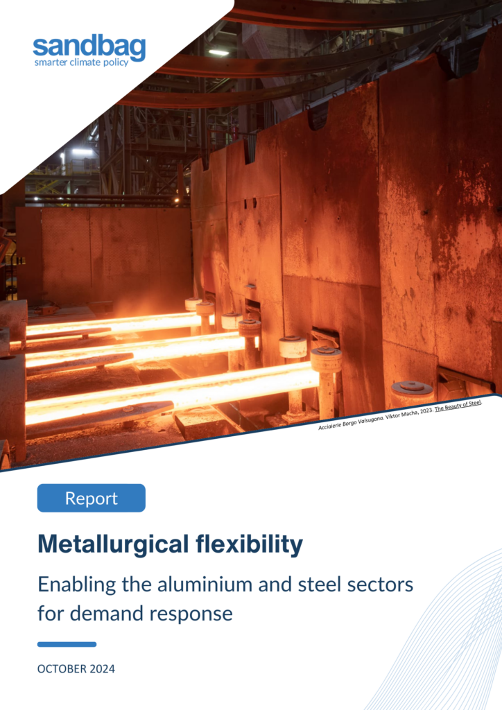 The image is the cover of a report titled "Metallurgical Flexibility: Enabling the Aluminium and Steel Sectors for Demand Response," published by Sandbag in October 2024. The top left corner features the Sandbag logo in blue with the tagline "smarter climate policy." Below the logo, an industrial scene is depicted, showing a glowing red-hot steel production process inside a factory. The lower section of the image contains the report's title in bold blue text, accompanied by a description in smaller text. The layout includes a diagonal design with rounded edges and blue lines. At the bottom right corner, a photo credit is visible, mentioning Acciaierie Borgo Valsugana and photographer Viktor Macha.